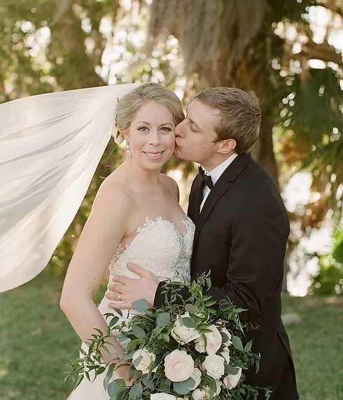 Groom kisses bride outdoors